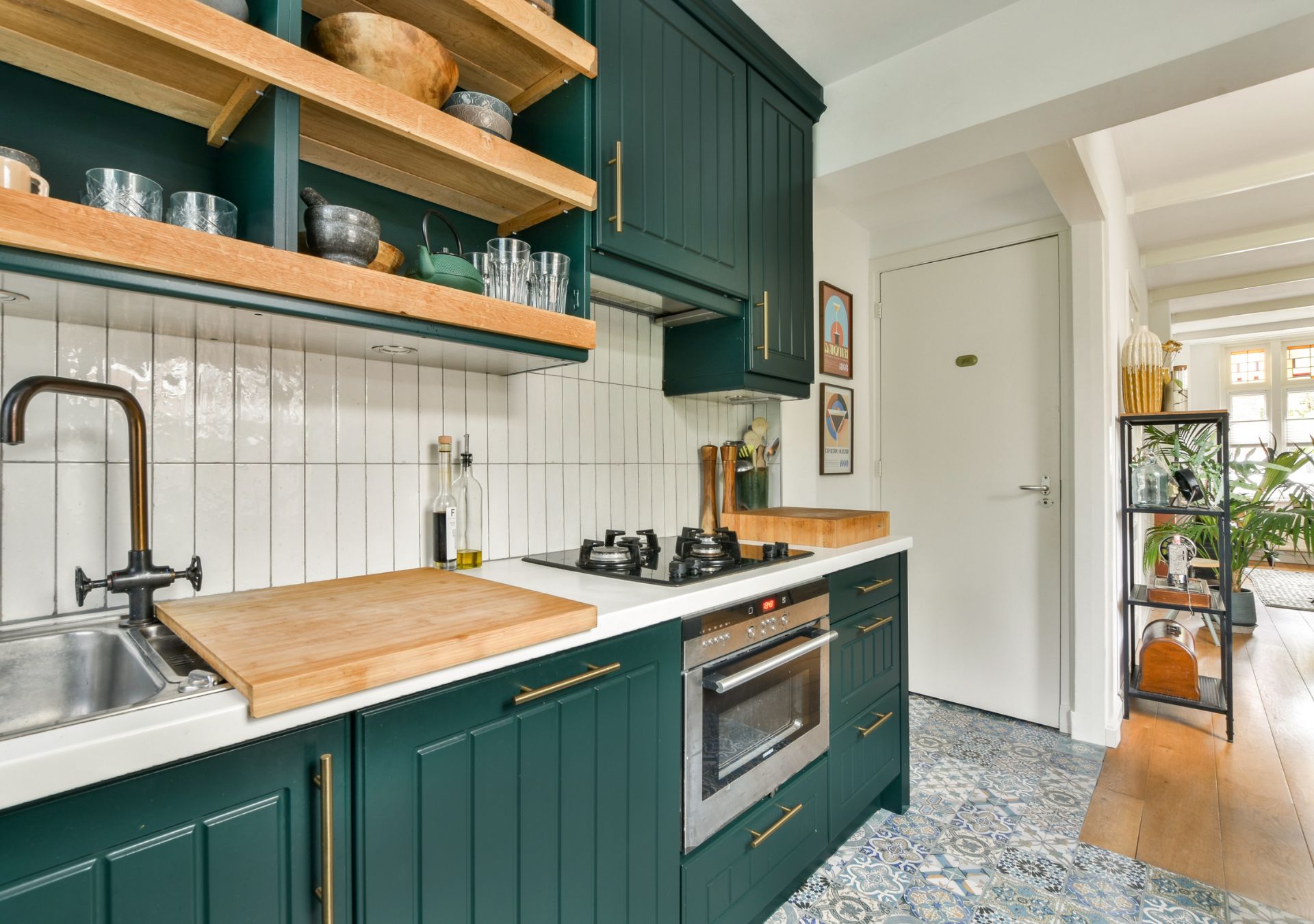 Kitchen with deep green cabinets, wood shelving and patterned tile backsplash
