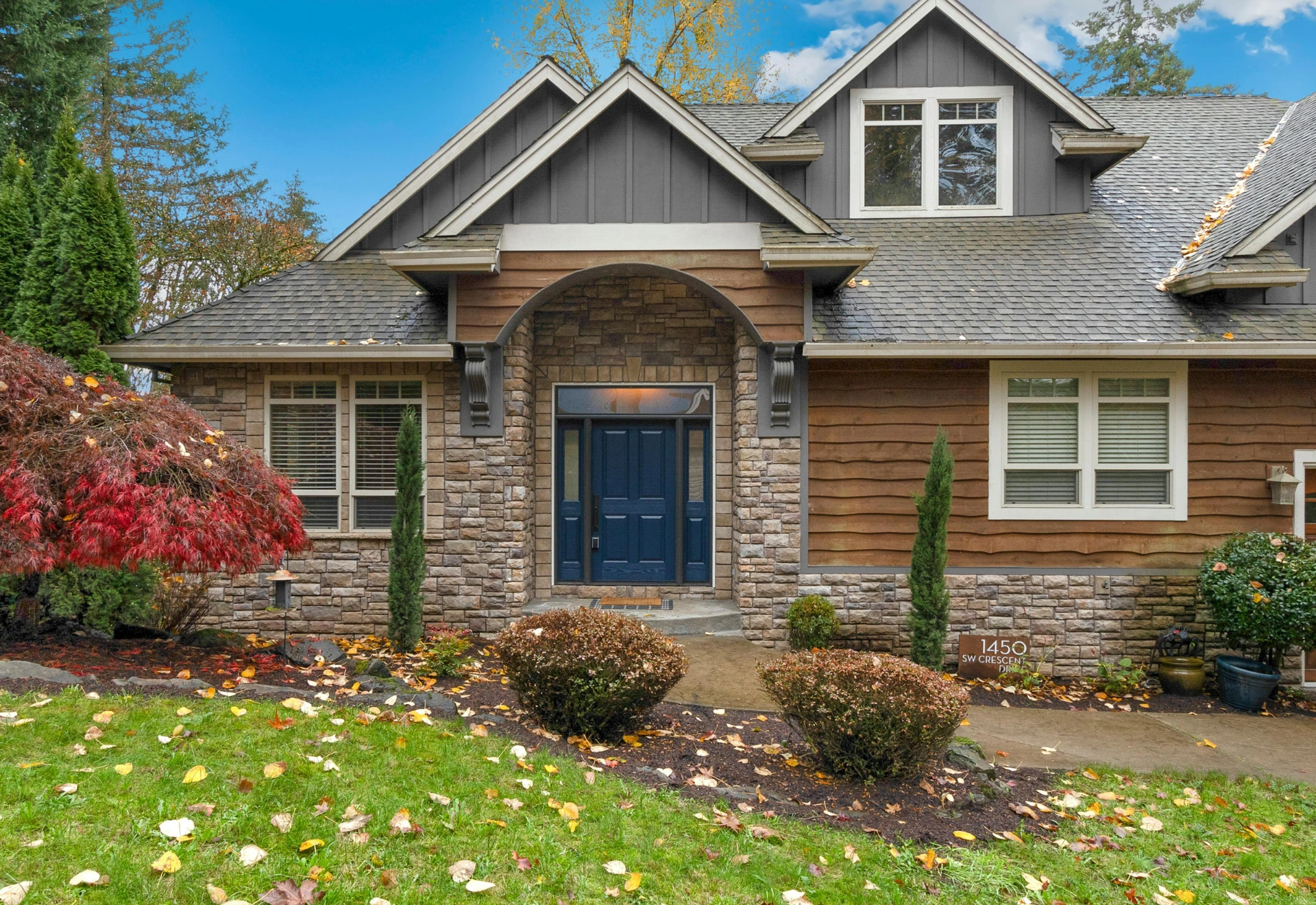 Stone-accented home with blue front door and autumn landscaping