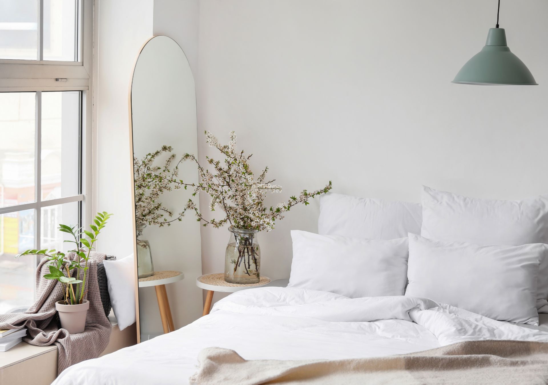 Bright bedroom with white bedding and plants by the window